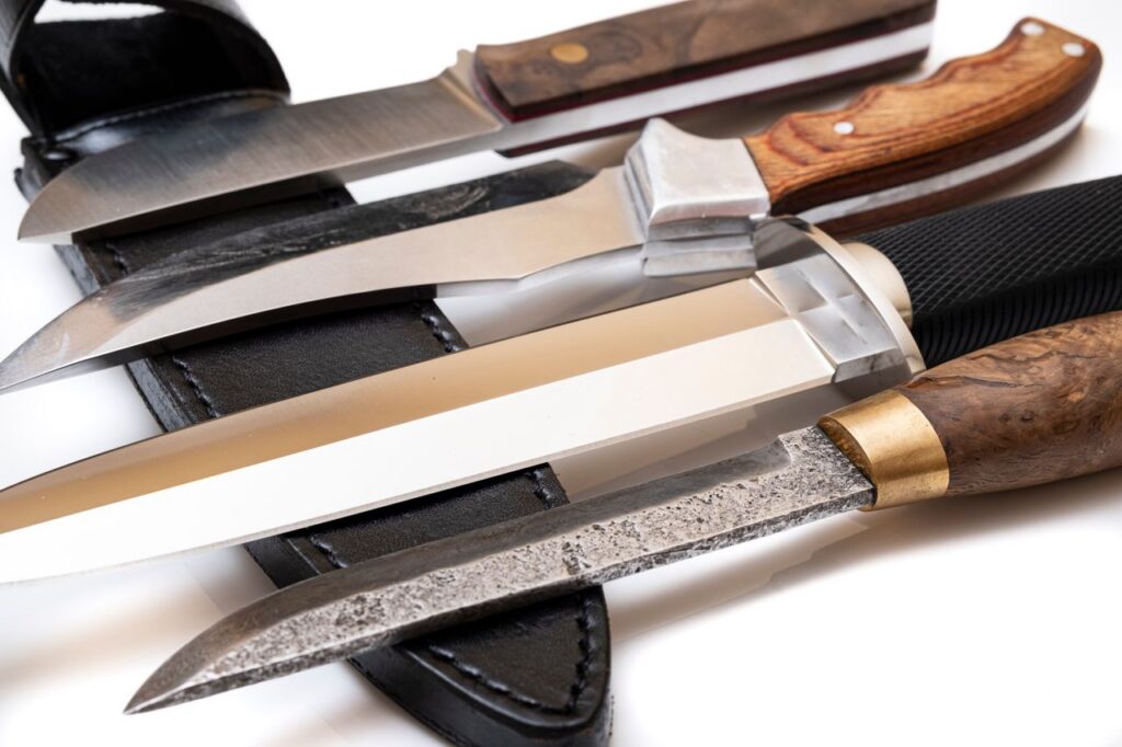 Detailed shot of various knives with wooden handles and leather sheaths, emphasizing craftsmanship.